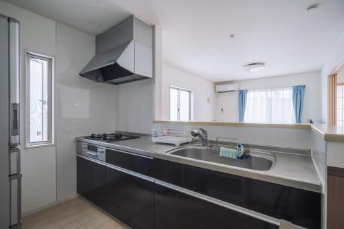 a kitchen with a sink and a stove at Comfort Miyabi -4号棟 in Yomitan