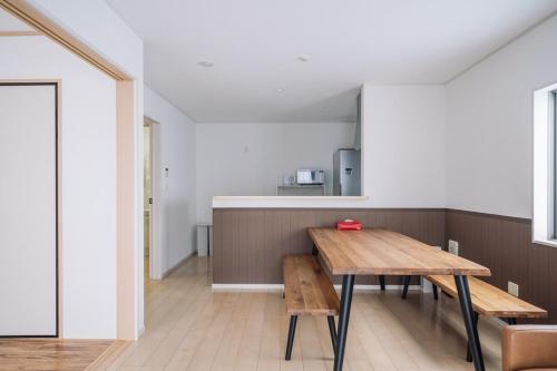 a dining room with a wooden table and benches at Comfort Miyabi -4号棟 in Yomitan