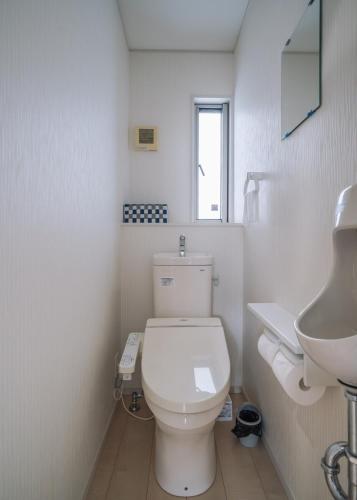 a bathroom with a white toilet and a sink at Comfort Miyabi -4号棟 in Yomitan