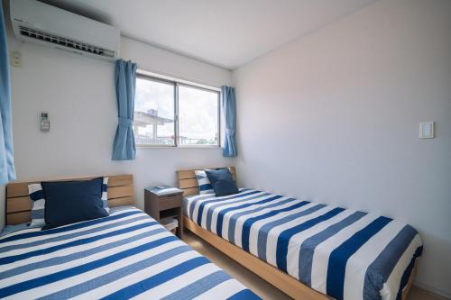two beds in a room with blue and white stripes at Comfort Miyabi -4号棟 in Yomitan