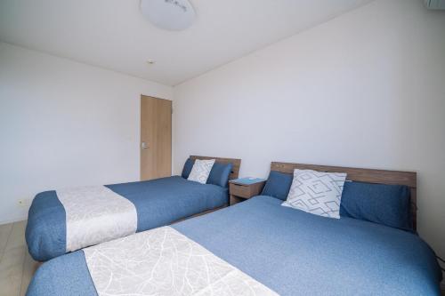 two beds sitting next to each other in a room at Comfort Miyabi -4号棟 in Yomitan