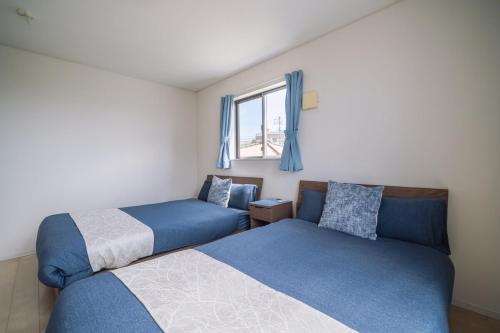 a bedroom with two beds and a window at Comfort Miyabi -4号棟 in Yomitan