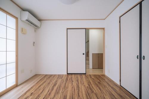 an empty room with white walls and wood floors at Comfort Miyabi -4号棟 in Yomitan
