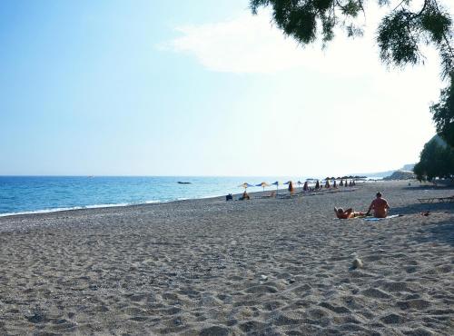 a group of people sitting on a beach at Saint George Hotel in Rodakino