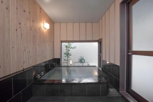 a bath tub in a room with a window at AMANE resort GAHAMA in Beppu