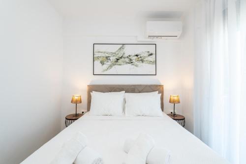 a white bedroom with a white bed with two lamps at White Dream Residential Complex in Skala Rachoniou