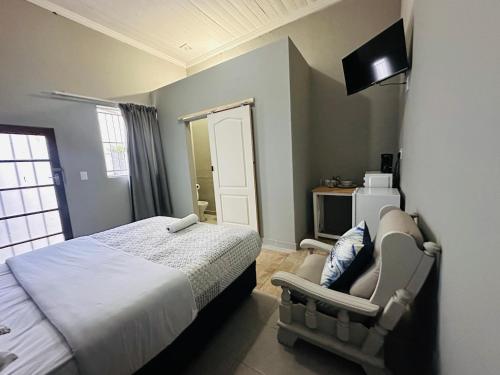 a bedroom with a bed and a chair and a television at Aruwaa in East London