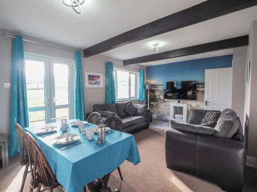 a living room with a blue table and a couch at Trenewydd Farm Holiday Cottages in Cardigan