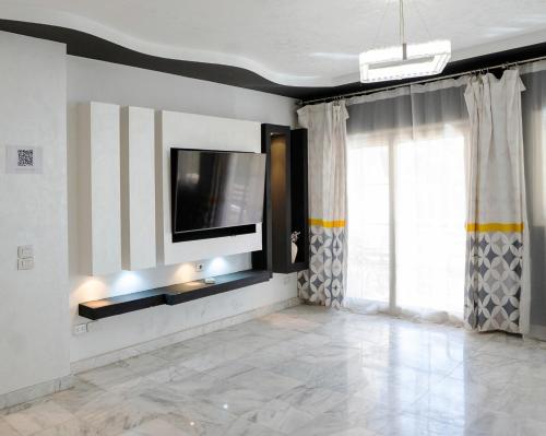 a living room with a television on a wall at Chic 2BR Apt 8min to Airport Family& work ready in Cairo