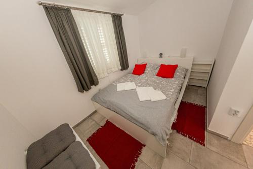 a small bedroom with a bed with red pillows at Villa BiBo in Linardići