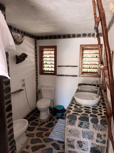 une salle de bain avec toilettes, baignoire et lavabo dans l'établissement Ravoravo beach house Nosy Be-Atanfondro, à Antafondro