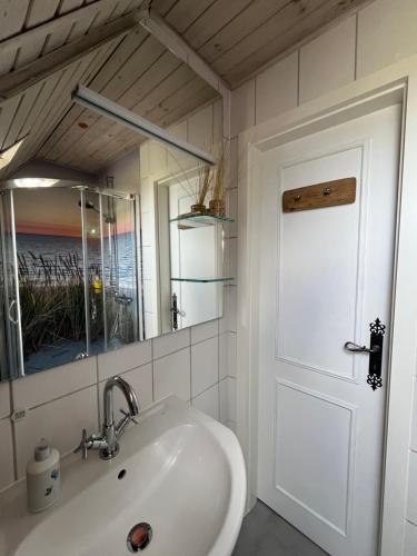 a bathroom with a sink and a mirror and a door at Mowennest Morsum in Morsum
