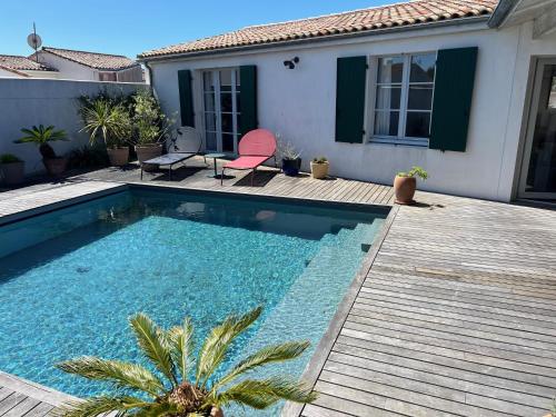 einen Pool mit einer Holzterrasse neben einem Haus in der Unterkunft La Villa des Alouettes avec piscine chauffee in Sainte-Marie-de-Ré