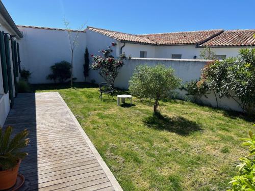 ein Garten mit einem Holzsteg und einer Bank in der Unterkunft La Villa des Alouettes avec piscine chauffee in Sainte-Marie-de-Ré