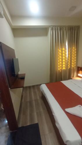 インドールにあるHotel WD Grand Staysのベッドと窓のあるホテルの部屋
