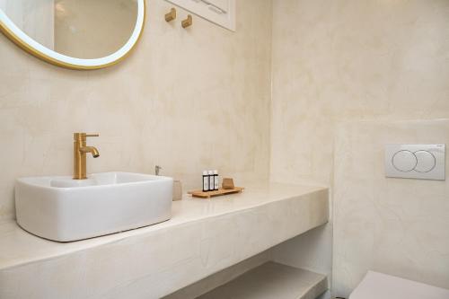 a white bathroom with a sink and a mirror at Tegame Apartments in Pythagoreio