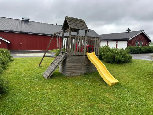 a wooden playground with a slide in the grass at Cozy 2 bedroom house on a farm just outside Lillestrøm in Lillestrøm