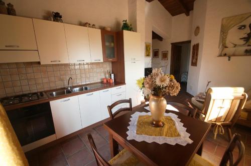 een keuken met een tafel met een vaas met bloemen erop bij Villetta Bouganvillea in SantʼAnna Arresi