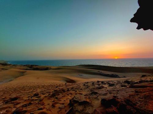 a sunset over the sand dunes on the beach at Moroccan Boho Surf House in Agadir