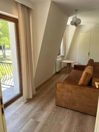a living room with a couch and a large window at Apartamenty Leśna Przystań Kazub nr 11 in Cieciorka