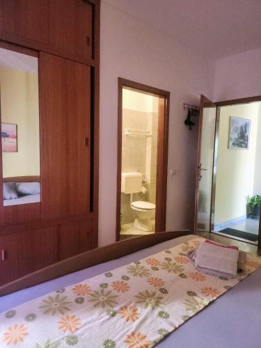 a bedroom with a bed and a bathroom with a toilet at room&4you in Supetar