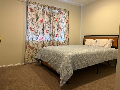 a bedroom with a bed with a floral shower curtain at Best aboard on Chapel Road in Auckland