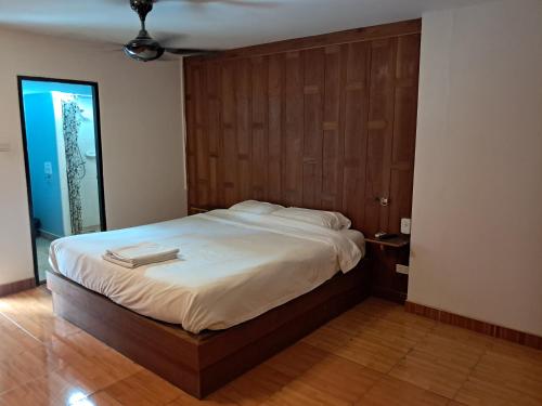 une chambre avec un grand lit avec une tête de lit en bois dans l'établissement Namtip Bar & Guesthouse, à Pattaya