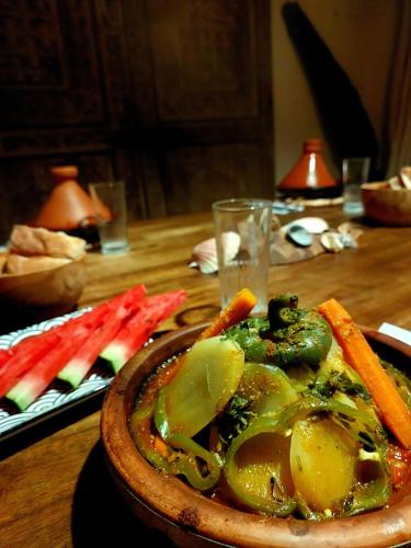 a bowl of food on a wooden table with vegetables at Moroccan Boho Surf House in Agadir