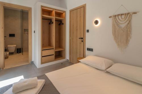 a white bedroom with a bed and a bathroom at Antonis Traditional House in Afantou