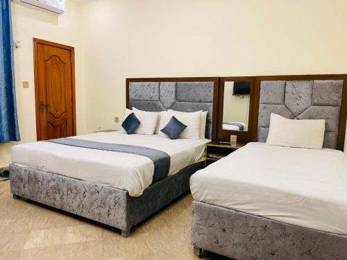 a hotel room with two beds and a mirror at Infinity Hotel in Lahore