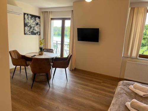 a living room with a table and chairs and a television at Apartamenty Leśna Przystań Kazub in Cieciorka