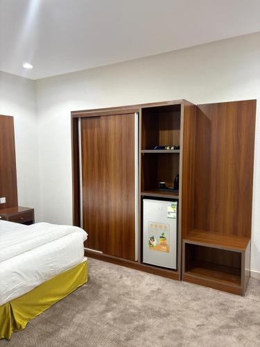 a bedroom with a refrigerator and wooden cabinets at شقق ابراج الخير in Abha