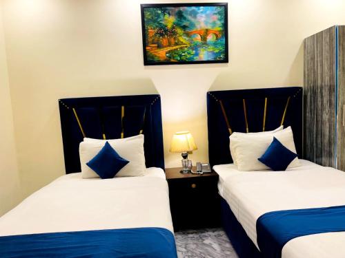 two beds in a hotel room with blue and white pillows at Infinity Hotel in Lahore