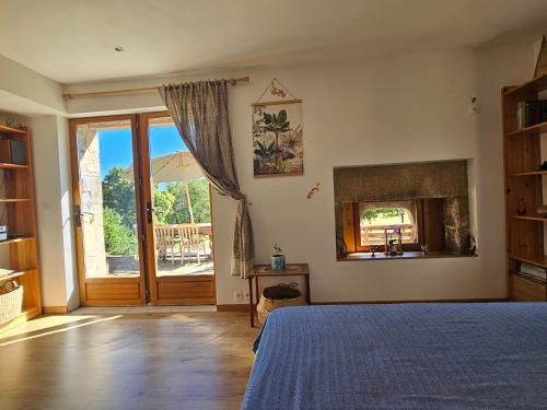 a bedroom with a bed and a fireplace and a door at Aux Grandes Rivieres in Madranges