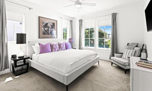 a white bedroom with a bed and a chair at Moonstruck in Santa Rosa Beach