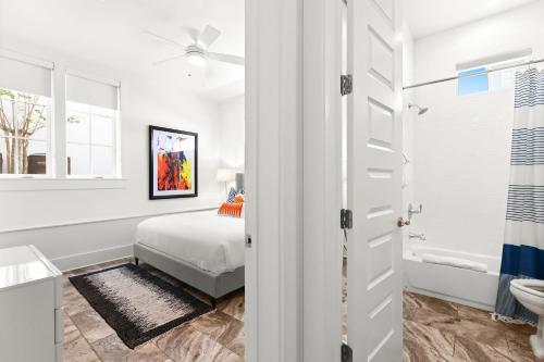 a white bedroom with a bed and a bathroom at Moonstruck in Santa Rosa Beach