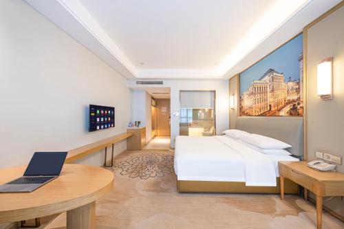 a bedroom with a bed and a laptop on a desk at Vienna Hotel Fuzhou Mawei Banzheng Cultural Scenic Area Branch in Fuzhou