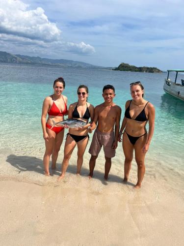 a group of four people standing on a beach at Riung Tiga Empat Tujuh Guesthouse in Riung