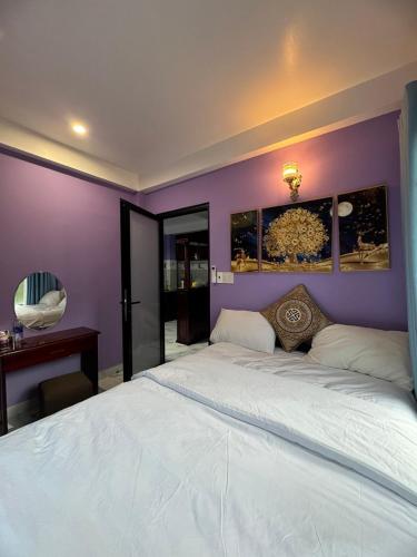 a bedroom with a white bed with a purple wall at Homestay PHƯỢNG HOÀNG in Lang Co
