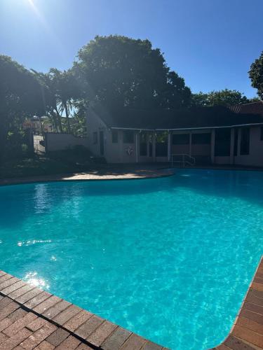 a large blue swimming pool in front of a house at BlueHive guesthouse Leisure in Port Edward
