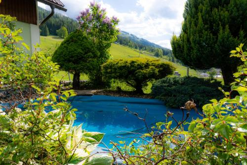 una piscina en un jardín con árboles en Gipfelglück Appartements - Ski in & Ski out, en Bad Kleinkirchheim