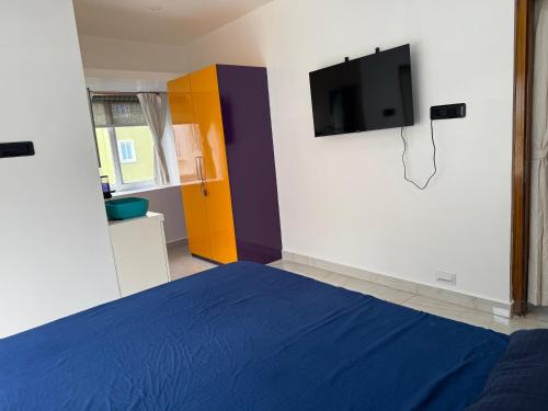 Un dormitorio con una cama azul y un televisor de pantalla plana. en Modern, Stylish & Luxurious 1 BHK stay,22, en Bhubaneshwar