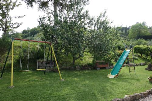 un parque infantil con 2 columpios y un tobogán en Casa Elisa, en Montaione