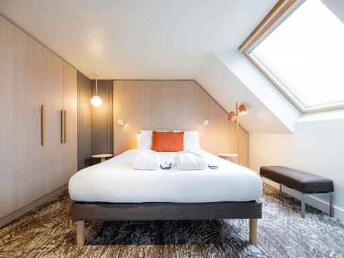 a bedroom with a large white bed with a skylight at Novotel Paris 13 Porte d'Italie in Le Kremlin-Bicêtre