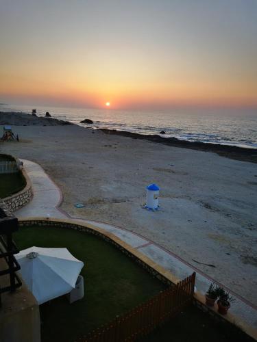 a view of the beach at sunset with the ocean at Sea Front Zen Chalet Families Only in Marsa Matruh