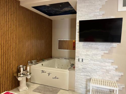 a bathroom with a tub and a tv on a wall at Terraforte Luxury Suite in Fisciano