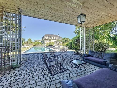 une terrasse avec un canapé et des chaises ainsi qu'une piscine dans l'établissement Maison de Maitre en Campagne Proximité Montagne et Mer Pau, à Bournos