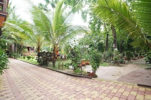 a cobblestone street with palm trees in a park at Whispering Woods Inn - Stay & Enjoy in Nature ! in Bolpur