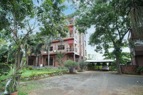 a large brick building with trees in front of it at Whispering Woods Inn - Stay & Enjoy in Nature ! in Bolpur