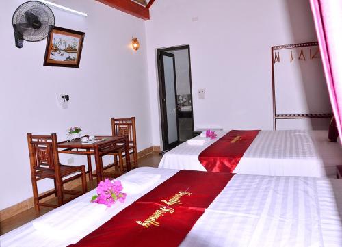 two beds in a room with a table and chairs at tam coc familyfriendly homestay in Vũ Lâm